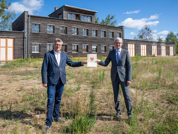 Dr. Fritz Brickwedde (links) nimmt den Fördermittelbescheid des Landes Brandenburg von Guido Beermann (rechts) entgegen. 