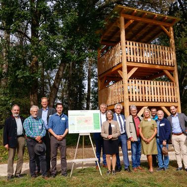 Menschen stehen vor dem neuen Aussichtsturm aus Holz im Wiesenbrütergebiet Thonstetten, Landkreis Freising.